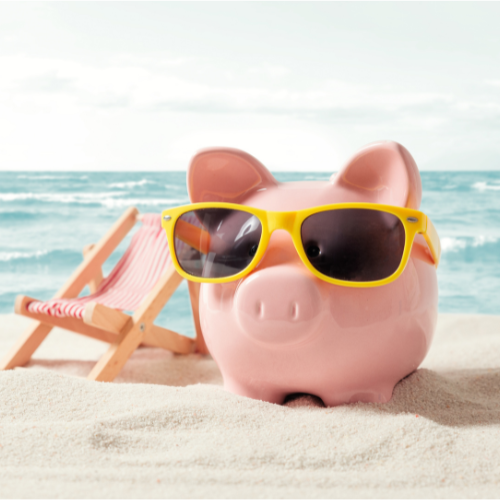 a pig bank wearing sunglasses next to a pink beach chair on a beach