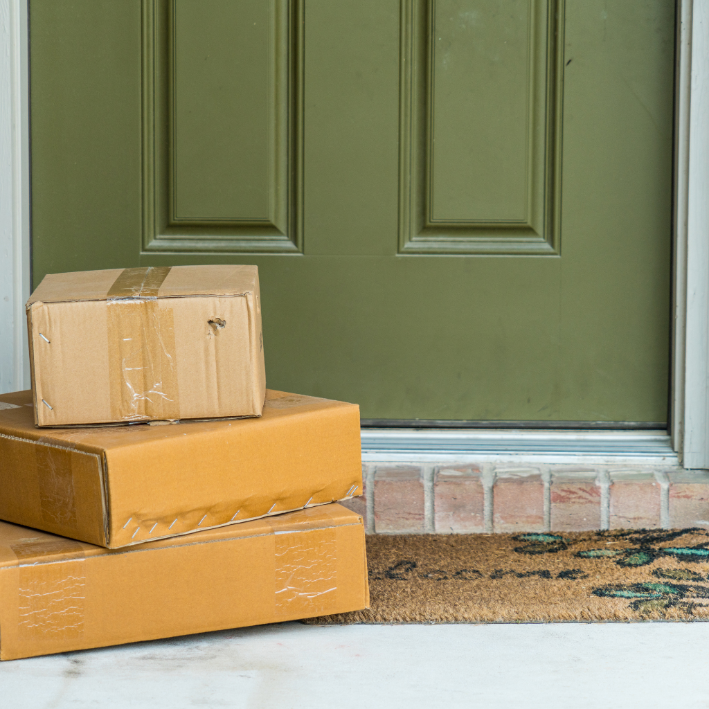 3 brown boxes sit in front of a green door