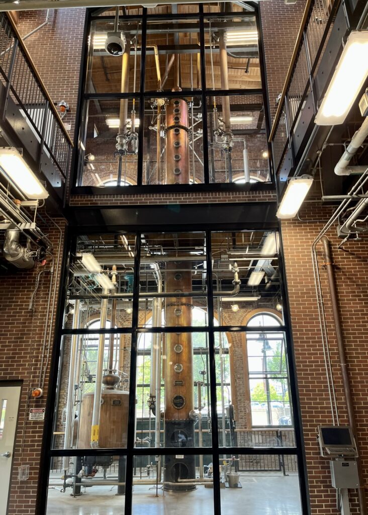 a tall distillery inside a room of glass