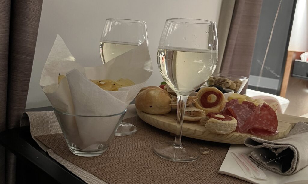 Two wine glasses with white wine. A plate of cheese and meats.