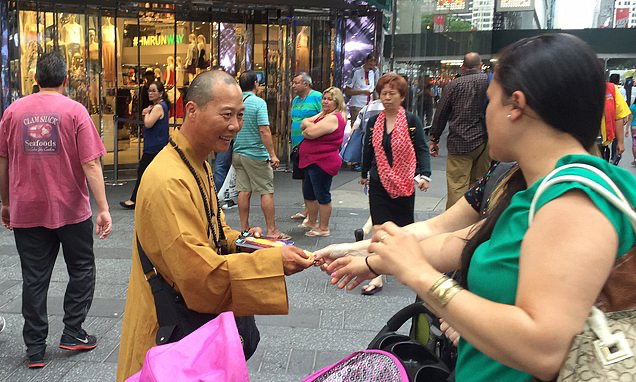 a smiling asian man giving a bracelet to a woman in a green shirt.