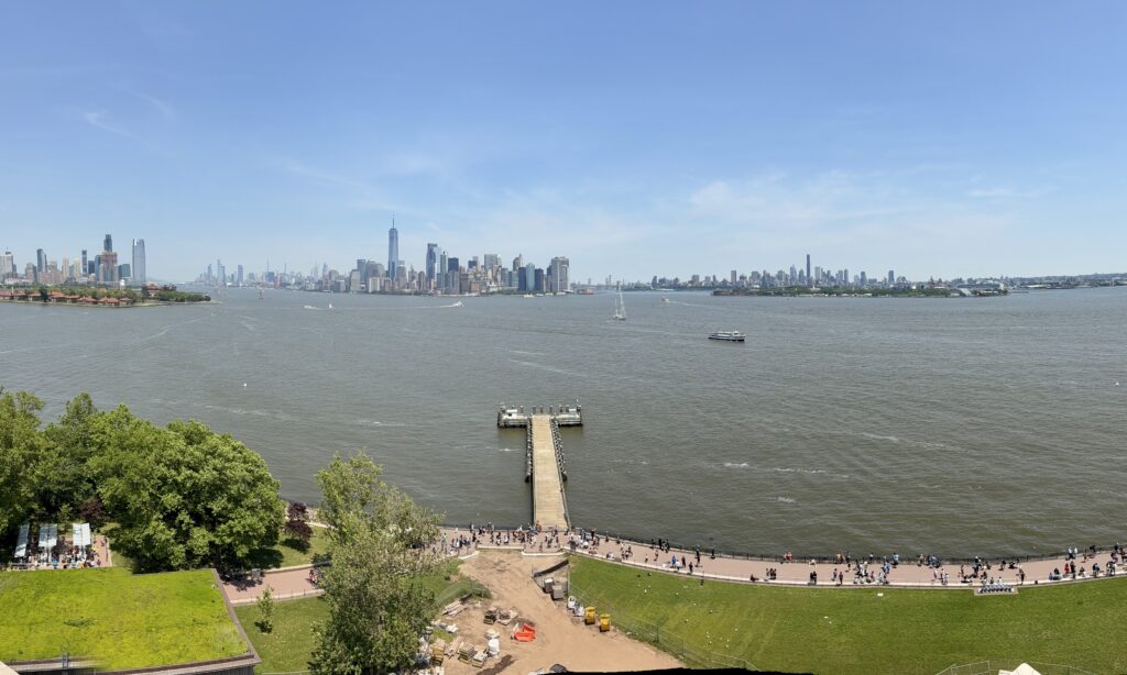 a city in the distance with skyskrapers, water and grass