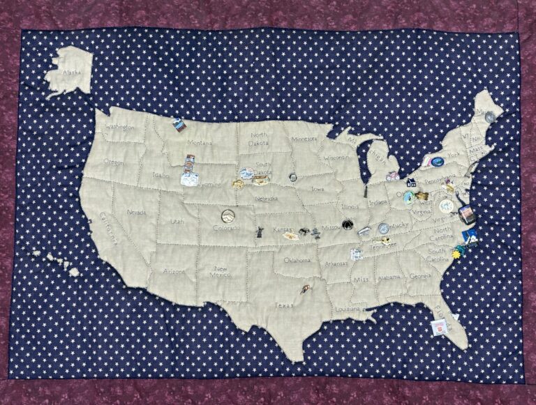 a us map in tan fabric on top of blue fabric trimmed with red fabric on a rod